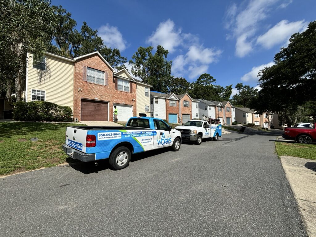 This photo shows a set of townhouses lining a street in a neighborhood. Water Works trucks line the sidewalk in front of the townhomes.